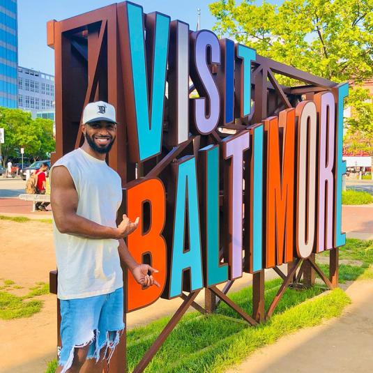 Man in front of the Visit Baltimore Sign