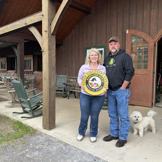 A couple standing outside of a bran from the Paradise Stables